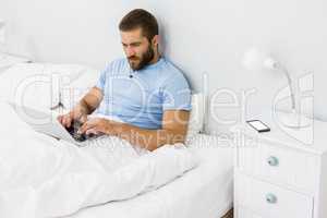 Man using laptop on bed