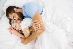 Man embracing woman while sleeping on bed