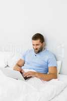 Man using laptop on bed