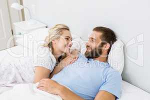 Couple smiling while relaxing on bed