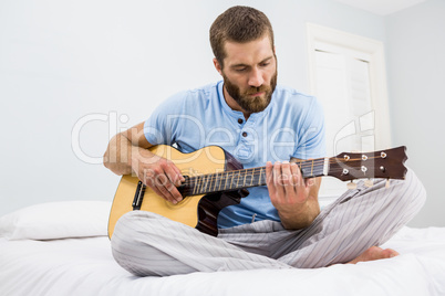 Man playing guitar in bed