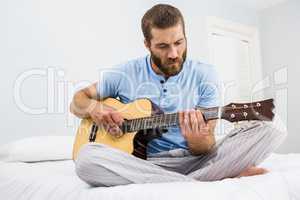 Man playing guitar in bed