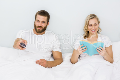 Man watching television while woman reading book