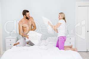 Couple having a pillow fight in bed