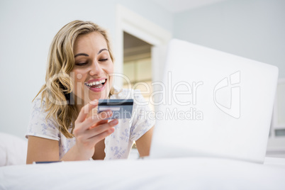 Woman shopping online on bed