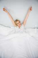 Woman stretching her arms in bed