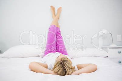 Young woman lying on bed with her feet up
