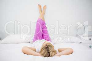 Young woman lying on bed with her feet up