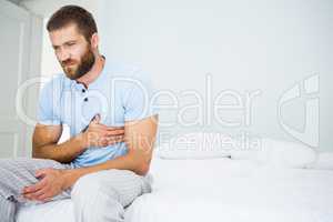 Young man having chest pain on bed