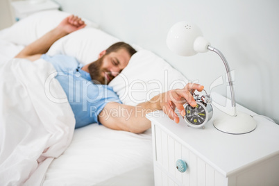 Sleeping man awakened by a alarm on bed