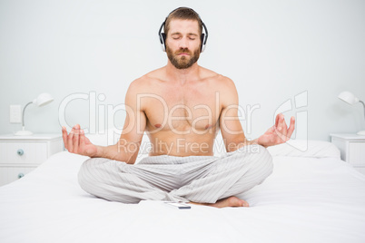 Man doing yoga while listening to music on bed