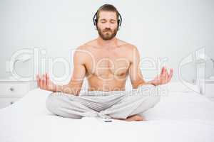 Man doing yoga while listening to music on bed