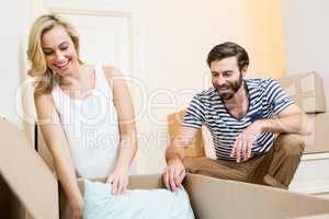 Young couple unpacking carton in their new house