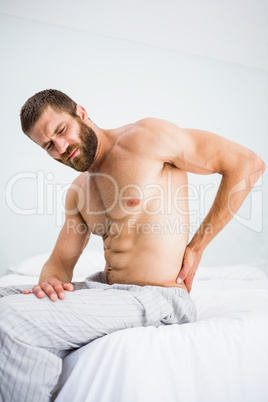 Man suffering from back pain on bed