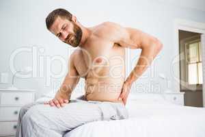 Man suffering from back pain on bed
