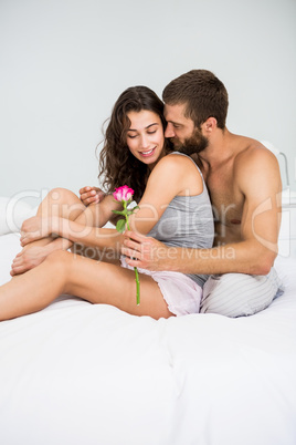 Man offering a rose to woman on bed