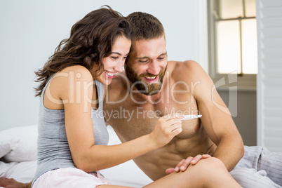 Happy couple looking at pregnancy test on bed