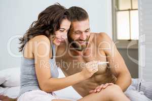 Happy couple looking at pregnancy test on bed
