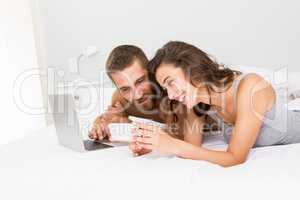 Woman showing mobile phone to man on bed