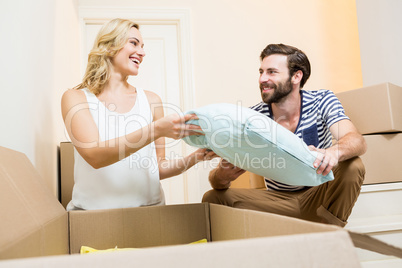 Young couple unpacking carton in their new house