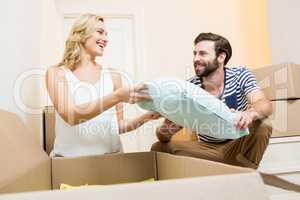 Young couple unpacking carton in their new house