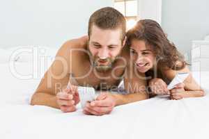 Man showing mobile to woman on bed