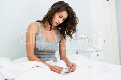 Young woman looking at medicine on bed