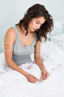 Young woman looking at medicine on bed
