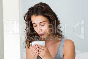 Close up of woman having coffee on bed