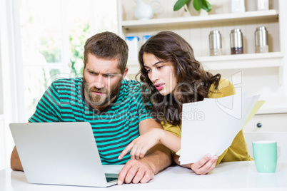 Couple paying their bills with laptop in kitchen