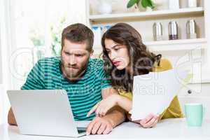 Couple paying their bills with laptop in kitchen