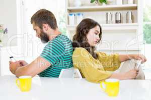 Couple sitting back to back and text messing on mobile phone