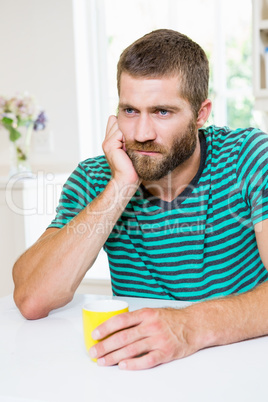 Upset man having coffee in kitchen