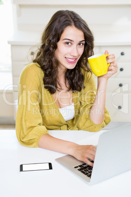 Close up of woman using laptop and having coffee