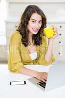 Close up of woman using laptop and having coffee