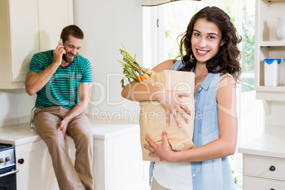 Woman holding groceries while man talking on mobile phone in kit