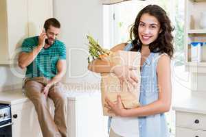 Woman holding groceries while man talking on mobile phone in kit