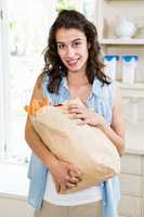 Beautiful woman holding groceries in kitchen