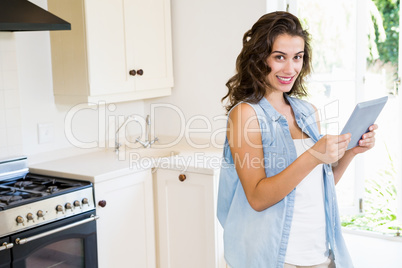 Young woman using digital tablet in kitchen