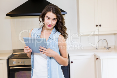 Young woman using digital tablet in kitchen