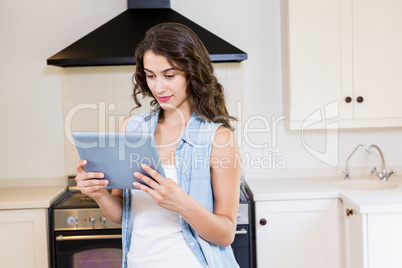 Young woman using digital tablet in kitchen