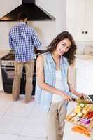 Woman chopping vegetables and man cooking on stove