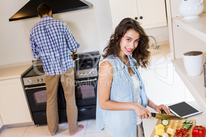 Woman chopping vegetables and man cooking on stove