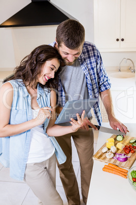 Woman using digital tablet and man chopping vegetables