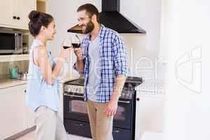 Young couple toasting wine glass in kitchen