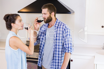 Young couple having red wine in kitchen