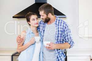 Young couple holding cup of coffee in kitchen