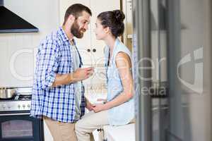 Happy young couple looking each other in kitchen