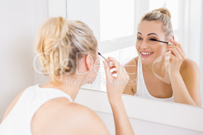 Young woman applying mascara in bathroom