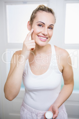 Young woman applying cream on face